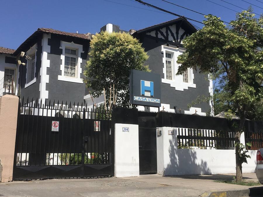 Un edificio de dos pisos con fachada blanco y negro, una entrada con reja y un letrero que dice 'CASA LYON'.
