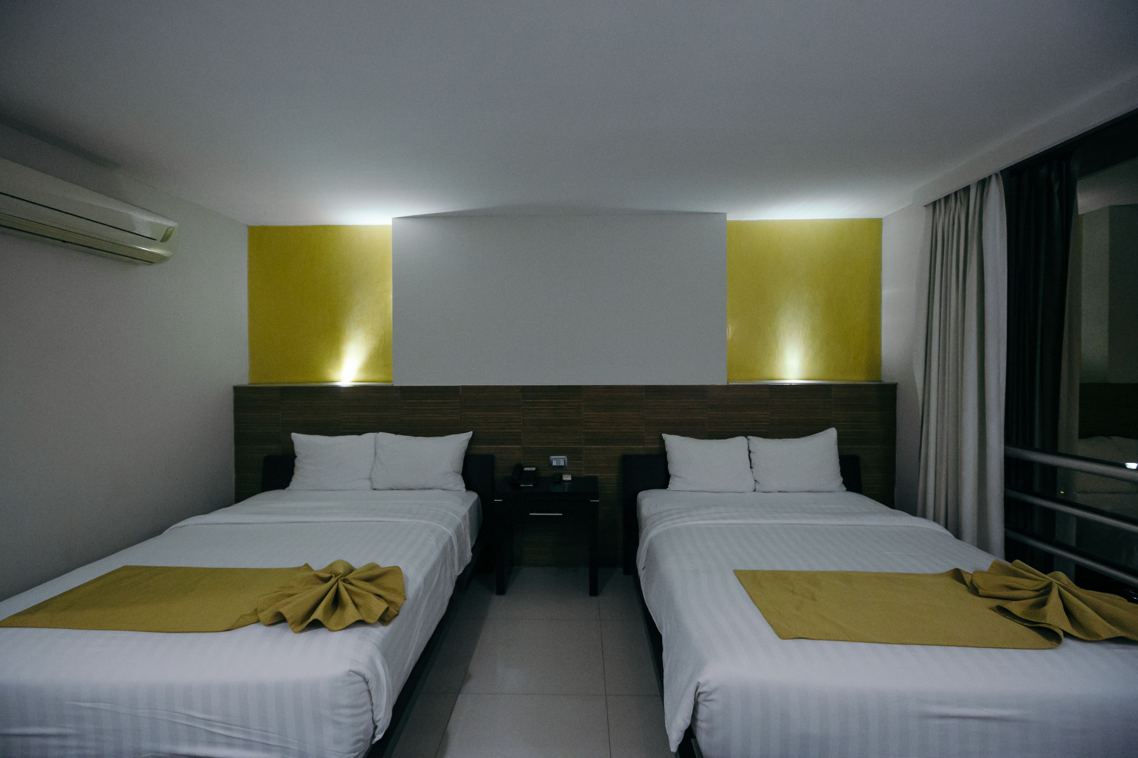 Habitació d'hotel amb dos llits, una taula de nit i una finestra amb cortines.