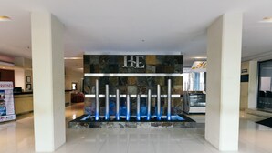 Un espace d’accueil au design moderne, comprenant un mur en pierre orné du logo de l’entreprise, un comptoir d’accueil et un écran numérique.