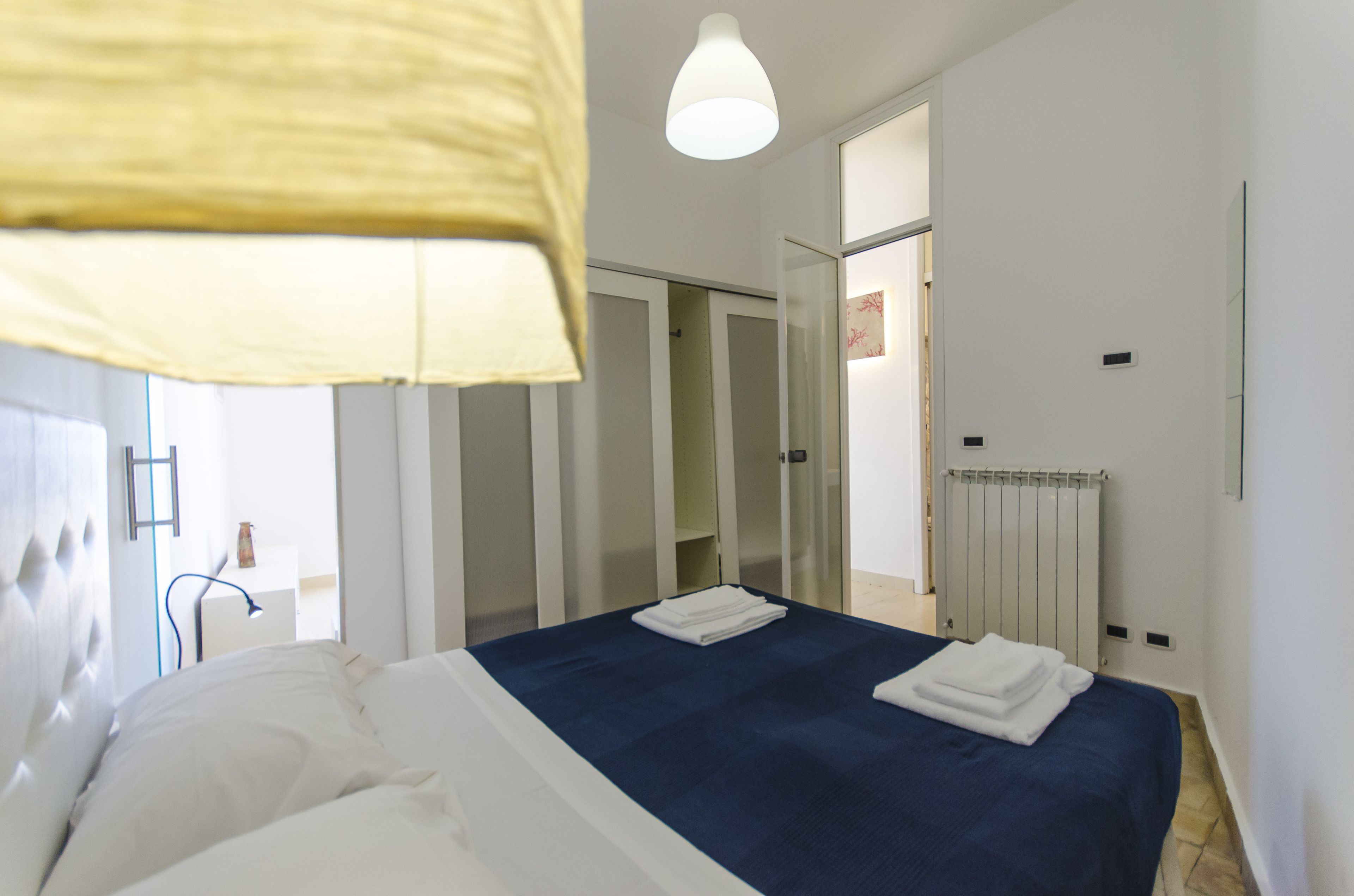 Ein Hotelzimmer mit Bett, Nachttischlampe, Heizkörper und Kleiderschrank.