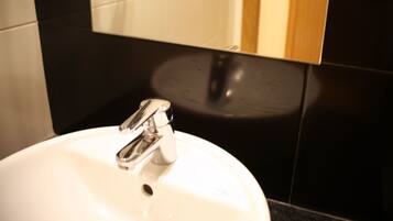 A bathroom sink with a chrome faucet, a mirror above it, and black tiles on the walls.