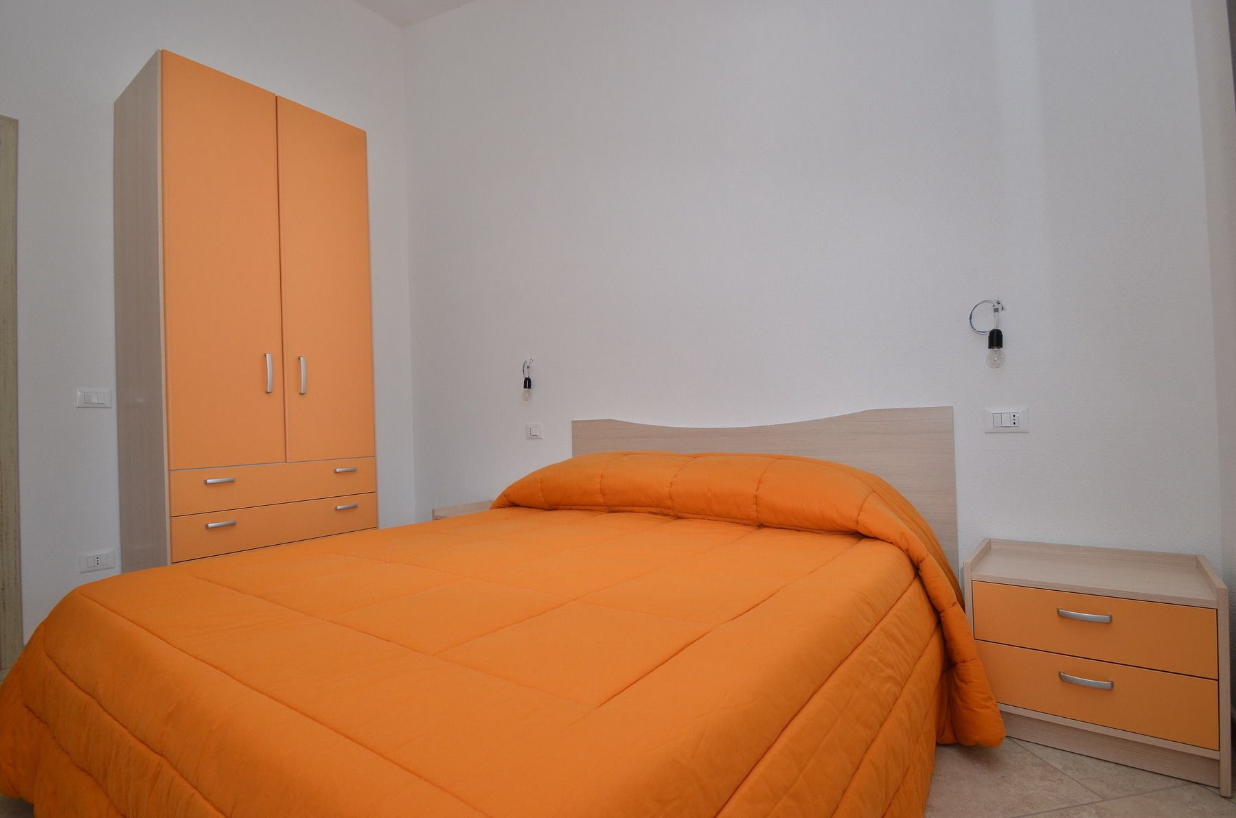 Een slaapkamer met een bed, een kledingkast en een nachtkastje.