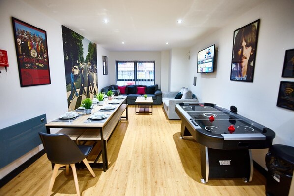 A modern living room with a pool table, a sofa, and a dining area with a table set for four. - Harrison Suite, Sleeps 14 (Liverpool)