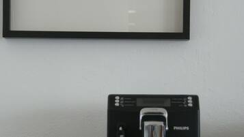 Ein gerahmtes Schwarz-Weiß-Foto über einer Kaffeemaschine auf einem Tisch.