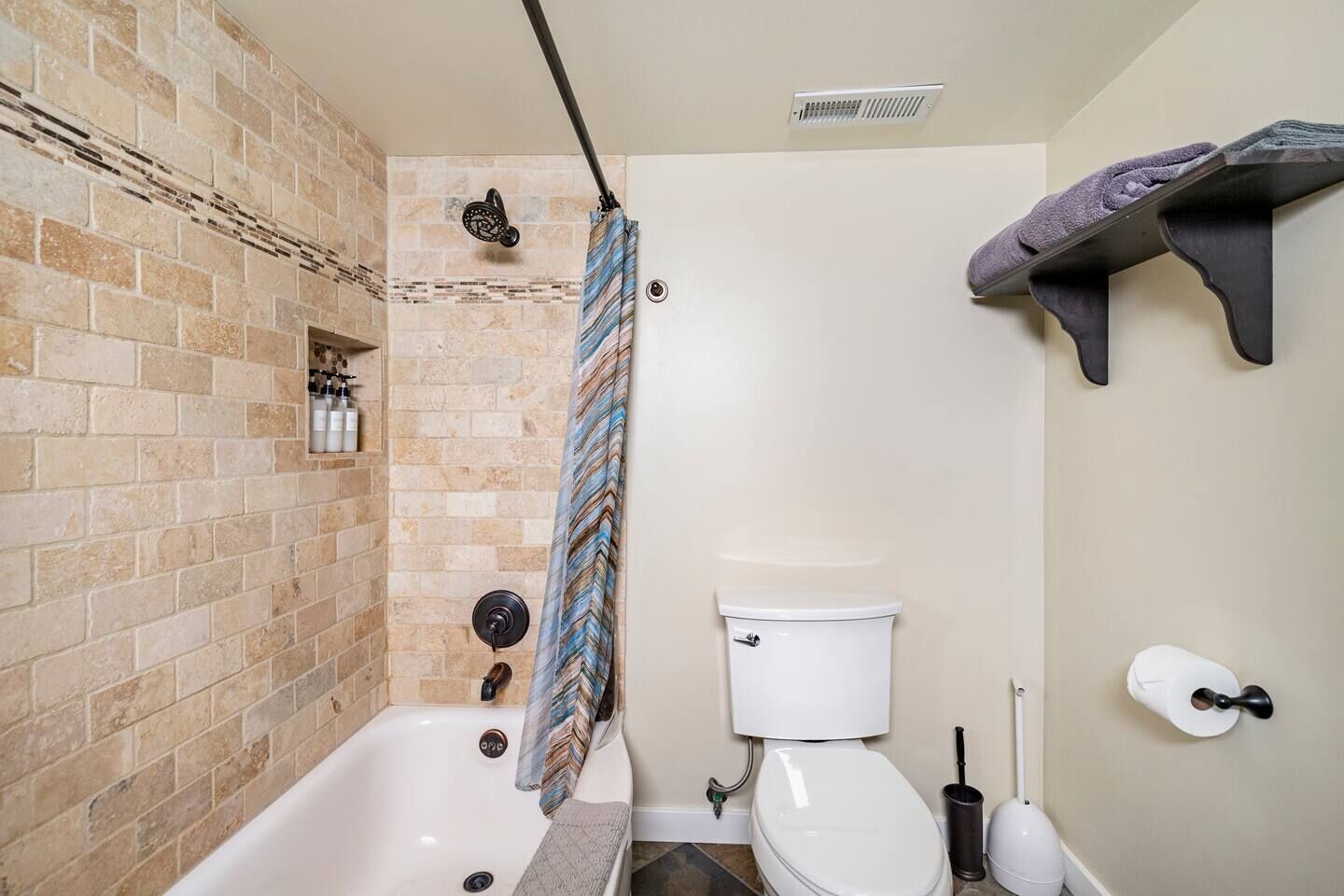 A bathroom with a bathtub, toilet, shower, and a towel rack.