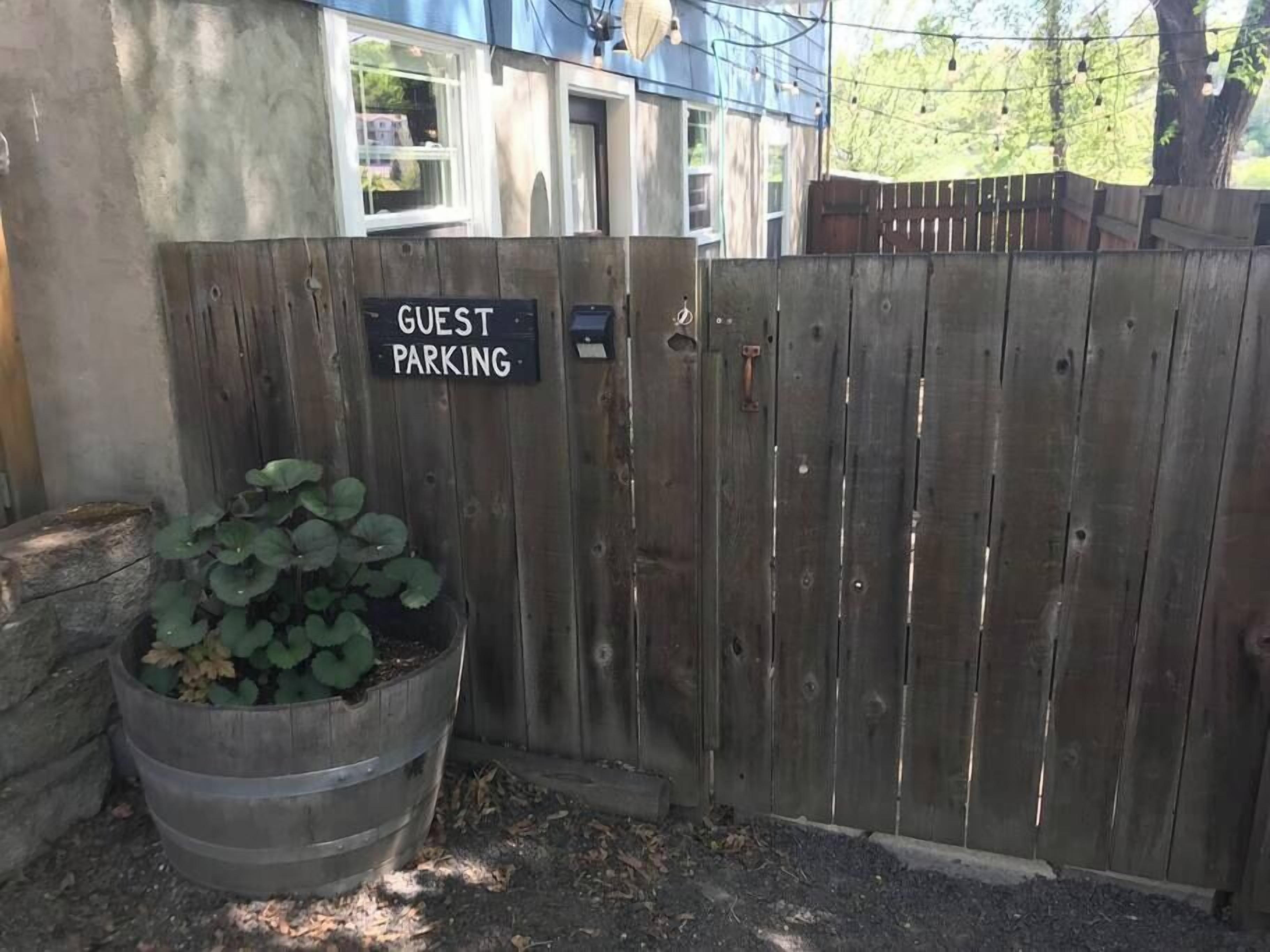 A wooden fence with a sign reading "GUEST PARKING" and a planter with green foliage.