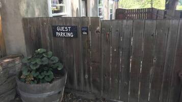 A wooden fence with a sign reading "GUEST PARKING" and a planter with green foliage.