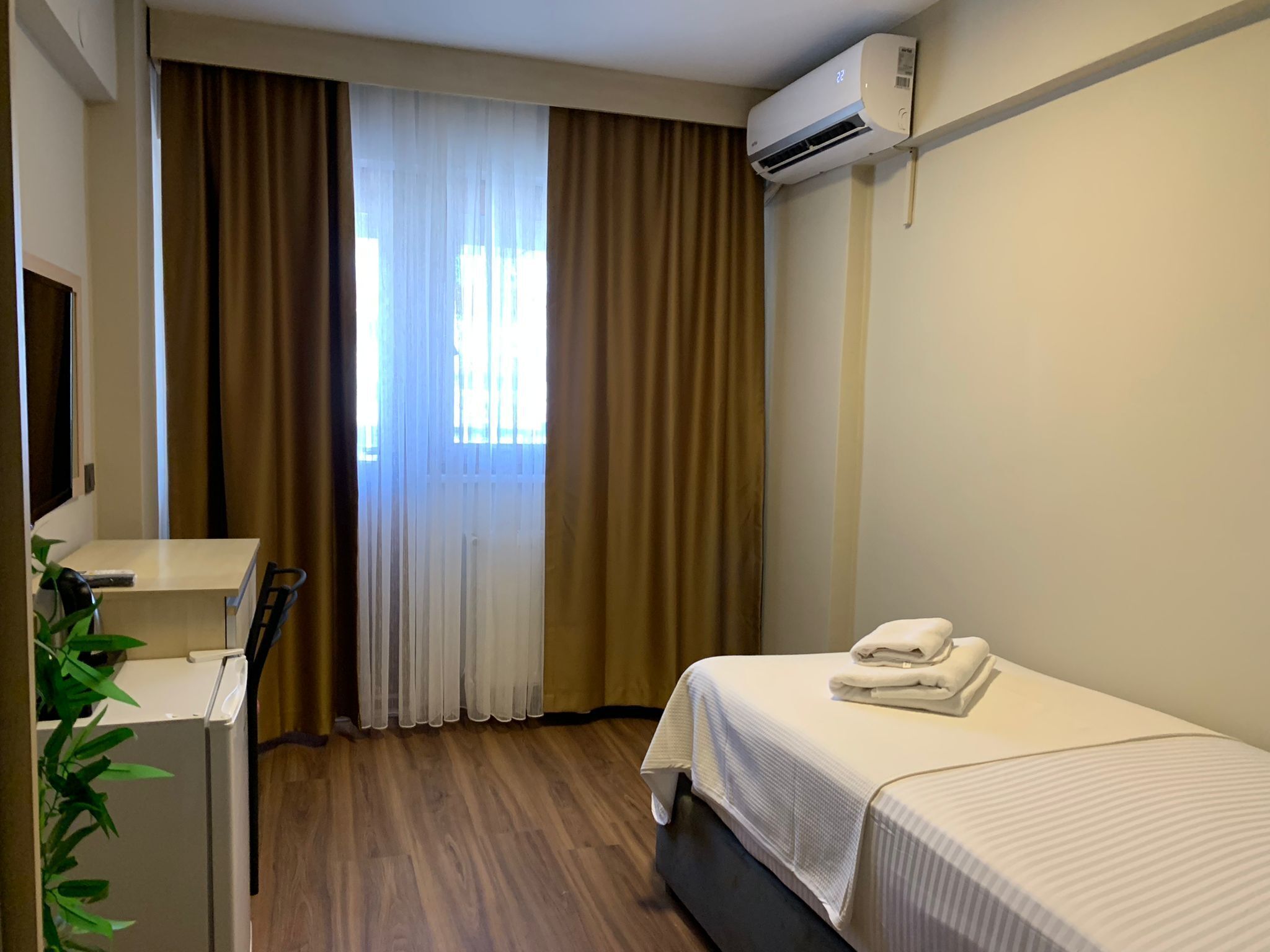 Een hotelkamer met een bed, bureau en airconditioning.