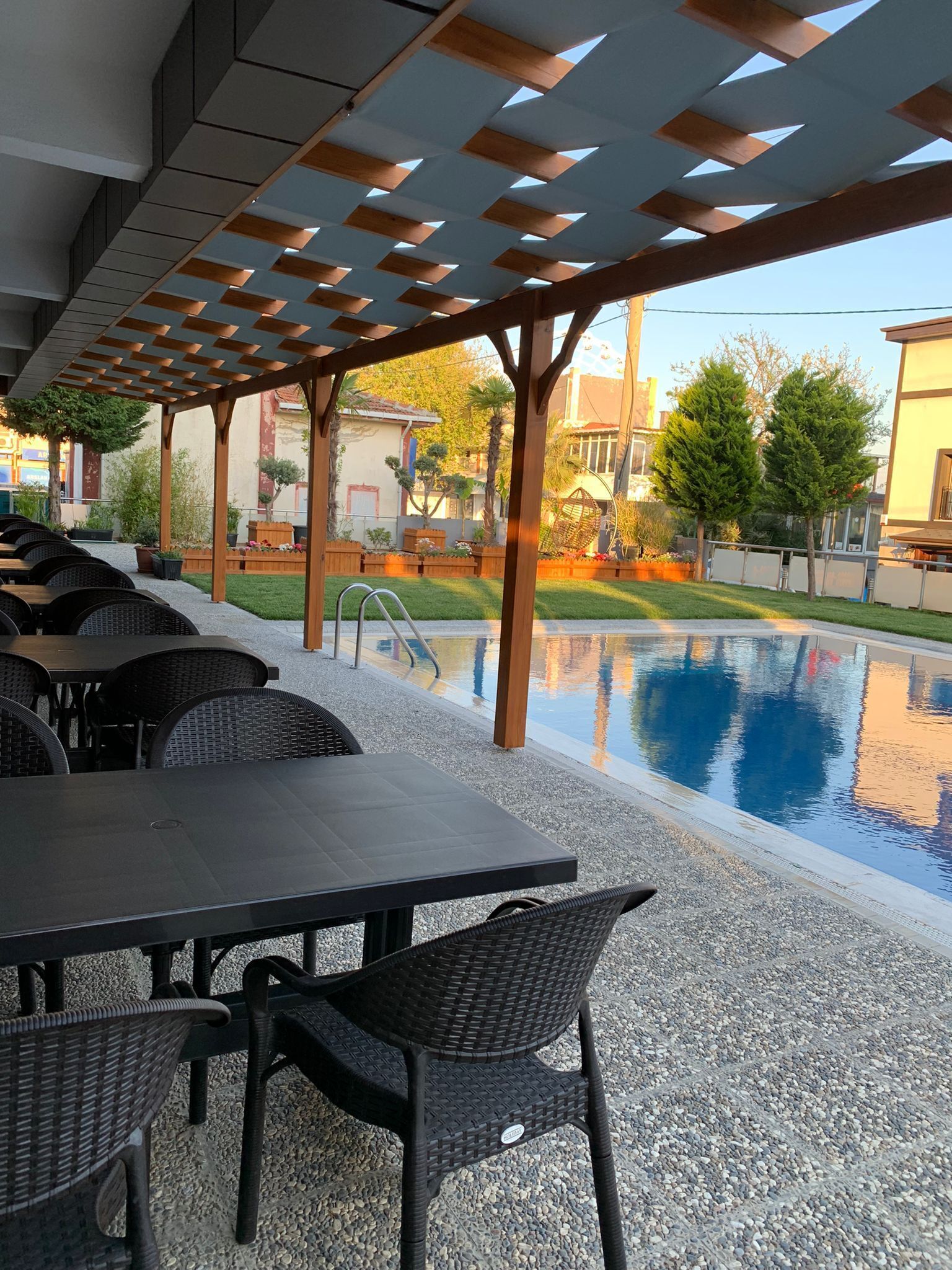Un área de estar al aire libre con mesas y sillas, una piscina y una pérgola.