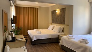 A hotel room with two beds, a desk with a chair, a coffee machine, and a TV mounted on the wall. - Akcay Zeytin Otel (Edremit)