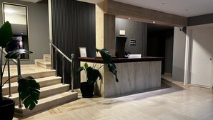 A modern interior with a staircase, a reception desk, and potted plants. - Akcay Zeytin Otel (Edremit)