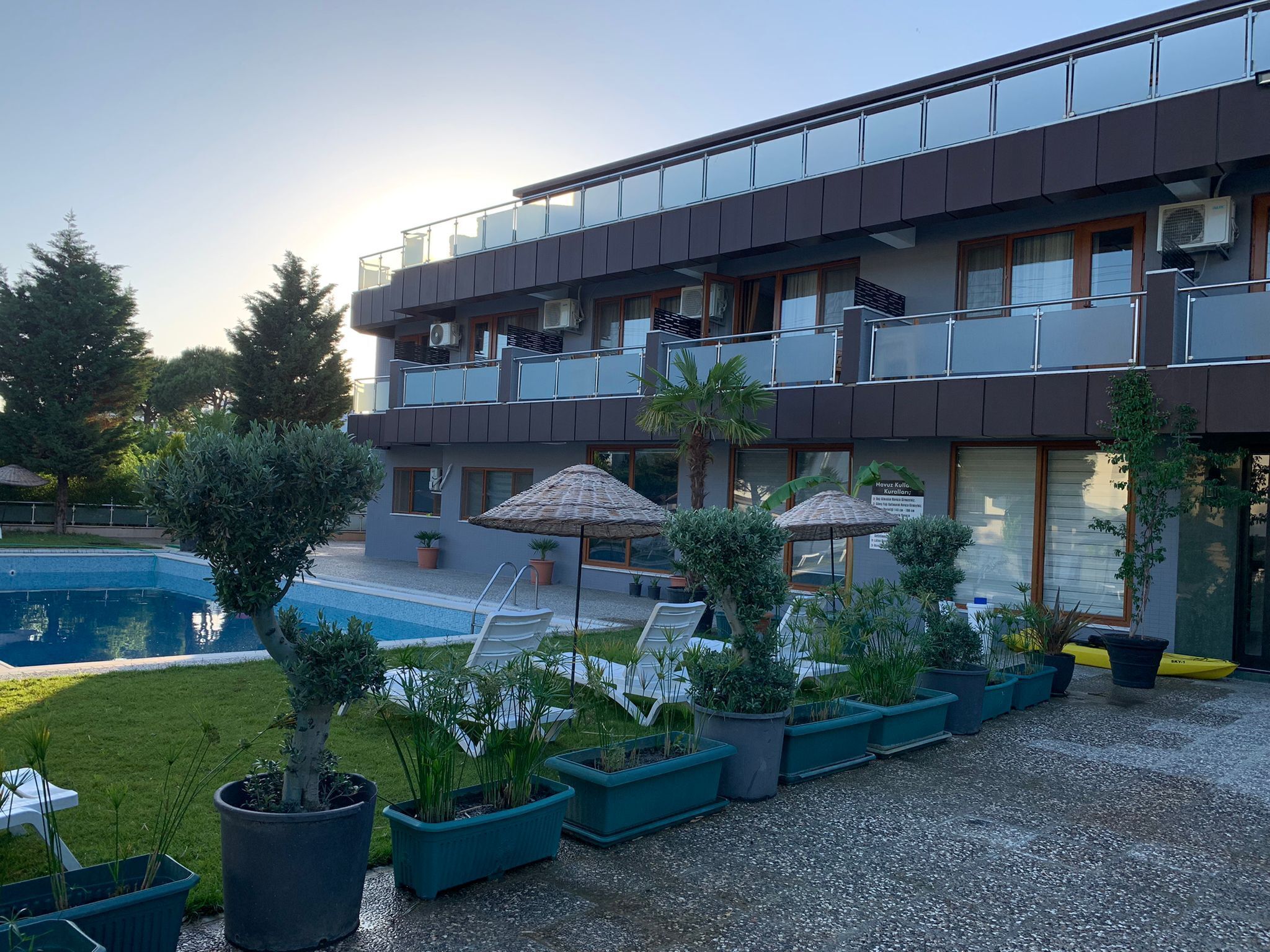 Un edificio moderno de dos pisos con piscina, asientos al aire libre y plantas en macetas.