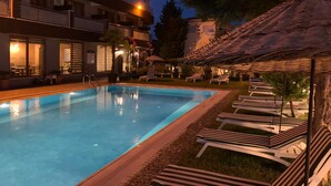 A swimming pool with lounge chairs and a building in the background. - Akcay Zeytin Otel (Edremit)