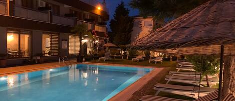A swimming pool with lounge chairs and a building in the background.