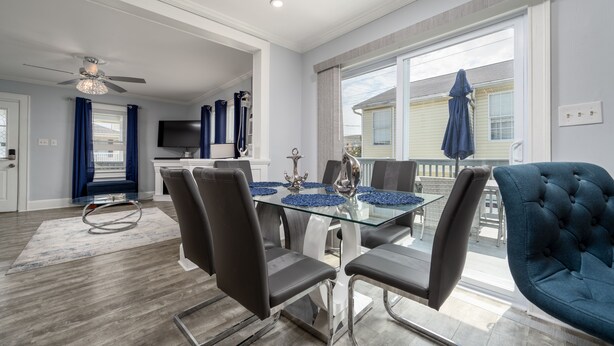 A modern dining area with a glass table, black chairs, and a blue upholstered chair. - Parrot Bay 2 bedroom Condo in Downtown OC with pool near the beach (Ocean City)
