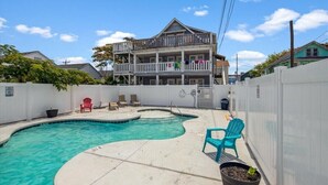 A two-story house with a backyard swimming pool, a fenced area, and a balcony with laundry hanging. - Parrot Bay 2 bedroom Condo in Downtown OC with pool near the beach (Ocean City)