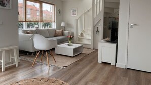 A modern living room with a sofa, coffee table, and a staircase leading to another level.