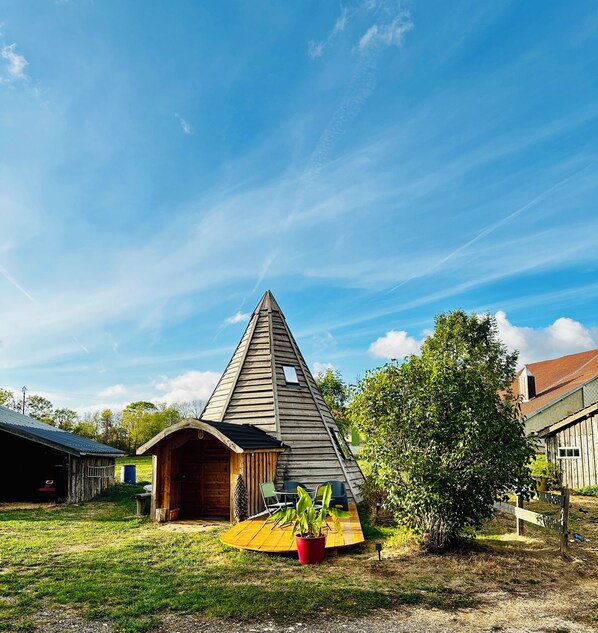 A wooden triangular structure with a small porch and a red planter.