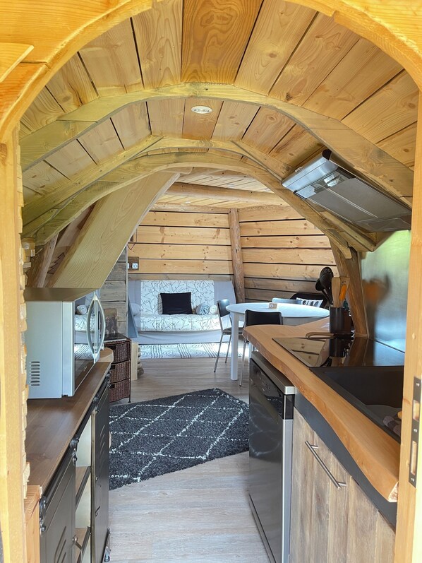 An interior with a kitchen area, a dining table, and a sofa. - A very comfortable wooden teepee in a village at an elevation of 830 meters. Perfect for cool evenings. (Plénisette)