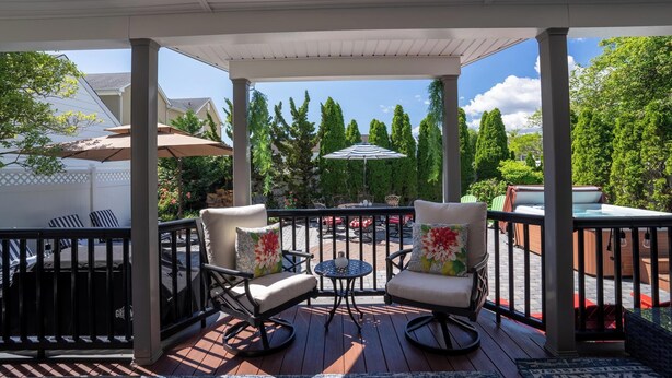 Eine überdachte Terrasse im Freien mit zwei Schaukelstühlen, einem kleinen runden Tisch und einem großen Sonnenschirm.