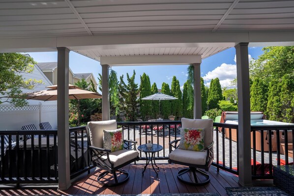 A covered outdoor patio with two rocking chairs, a small round table, and a large umbrella.