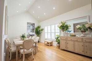 A modern kitchen with wooden cabinets, a dining table with chairs, and a large window with blinds. - 2 short blocks  to the beach. FULLY RENOVATED HOUSE  WITH NEW HOT TUB. (Point Pleasant Beach)