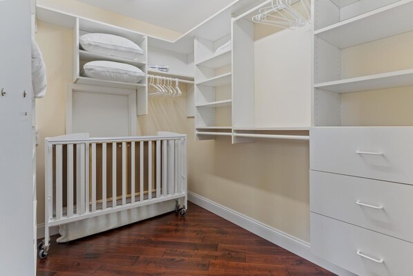 A walk-in closet with open shelves, a white storage unit, and a white crib. - 2 short blocks  to the beach. FULLY RENOVATED HOUSE  WITH NEW HOT TUB. (Point Pleasant Beach)