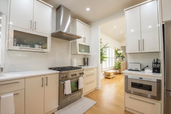A modern kitchen with stainless steel appliances, white cabinetry, and a central island.