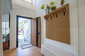 Passadís amb una banca de fusta, una porta que dona a l'exterior i una prestatgeria penjada a la paret amb plantes.