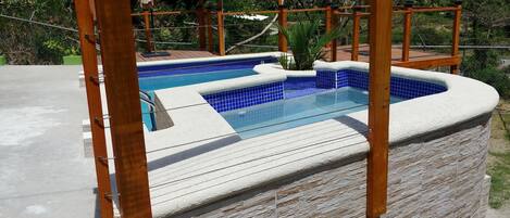 A swimming pool with a stone exterior and a wooden deck.