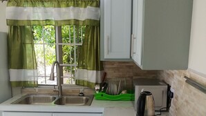 A compact kitchen with a gas stove, two sinks, and a window with green curtains. - 1 Modern A/C apartment with pool. Walking distance from beach, shop & restaurant (Castries)