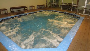 Un jacuzzi con una terraza de madera y bancos alrededor.