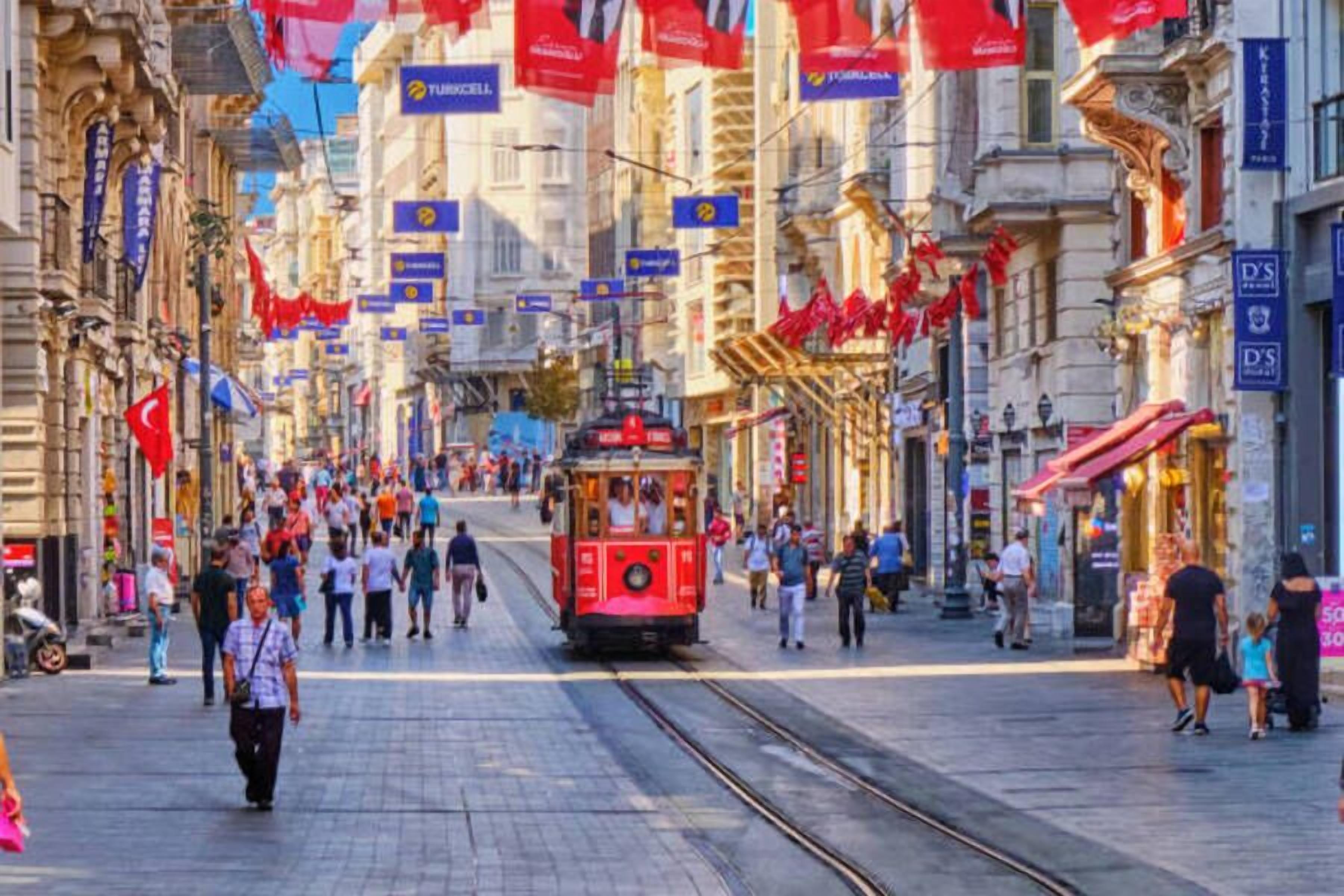 A bustling street with a red tram, historic buildings, and people walking.