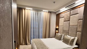 Ein modernes Schlafzimmer mit einem großen Bett, einer Kopfteil mit gepolstertem Design und einem Nachttisch.