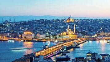 A cityscape at dusk with a prominent mosque and a bridge over a river.