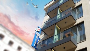 Ein Hotel mit modernem Design, das mehrere Balkone mit Glasgeländern und ein Schild mit der Aufschrift ‚Vier-Sterne-Hotel‘ zeigt.