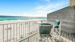 A balcony with a view of the beach and ocean.