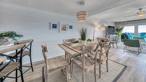 A modern dining area with wooden furniture, a central table, and a ceiling fan.