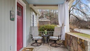 A porch with a red door, two chairs, a small table, and a welcome sign. - Bright & Cozy Bungalow Close To Downtown! Dogs Stay Free! (Hendersonville)