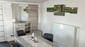 A modern dining area with a rectangular table, six chairs, and a large mirror above the table.