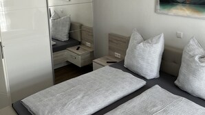 A modern bedroom with a bed, bedside tables, a mirror, and a painting of a mountain landscape.