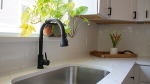 Una cocina con un lavamanos de acero inoxidable, un grifo negro y una ventana con vista a un edificio.