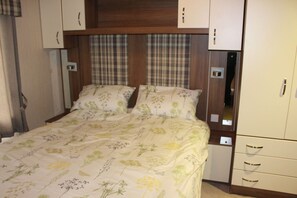 A bedroom with a bed, two bedside tables, a wardrobe, and a mirror. - Glen View - mobile home with spectacular alpine and loch view (Taynuilt)