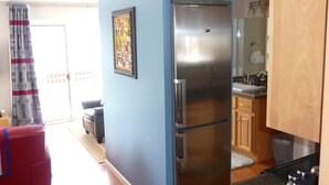 A compact kitchen with a refrigerator, wooden cabinets, and a small countertop. - Architect designed 1-bdrm/+wall-bed, 15-min walk to downtown, Patio/balcony/View (Estes Park)