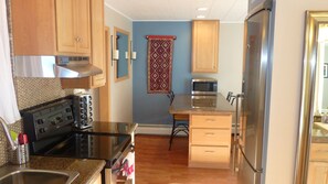 A compact kitchen with wooden cabinets, a stove, a microwave, and a refrigerator.