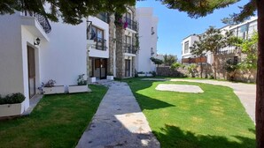 Un edificio moderno con un camino empedrado, paredes blancas y un césped cuidado.