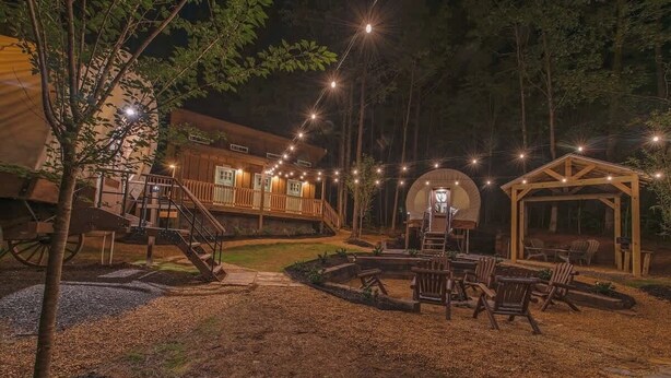 Eine Holzhütte mit Terrasse, Sitzgelegenheit im Freien und Lichterketten.