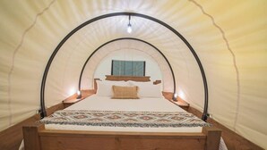 Ein Zelttyp-Zimmer mit Bett, Fenster und einer Hängelampe.