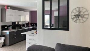 Een moderne keuken met witte kastjes, een centraal eiland en een grote wandklok.