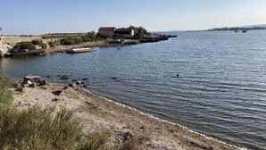 Een kustlandschap met een huis aan het water, boten en een rotsachtige kustlijn.